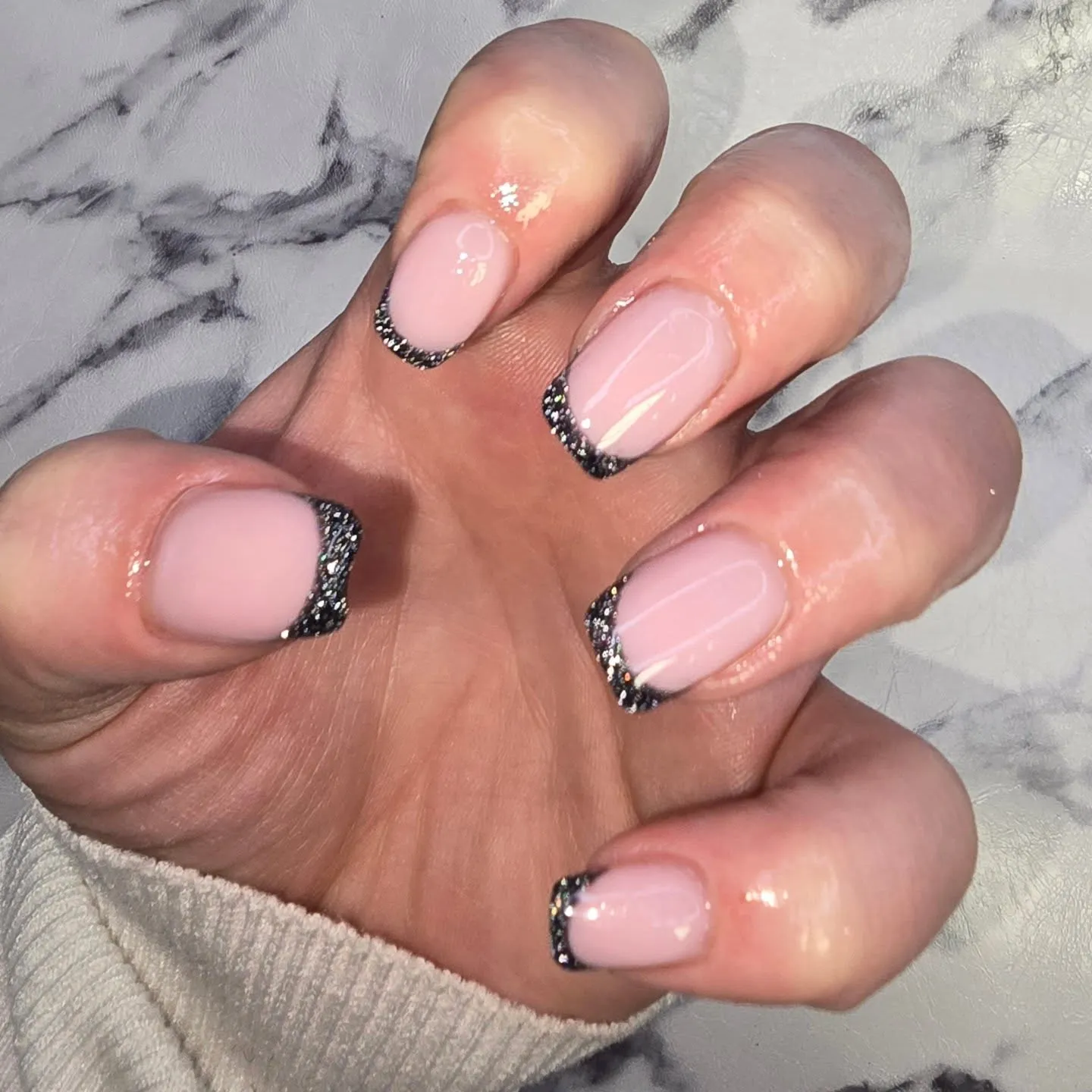 This black glitter French tip design adds a modern edge to a classic look. A soft pink base keeps the manicure clean and wearable, while fine black glitter tips create contrast without feeling heavy or dramatic. It’s a sleek, minimalist style that works just as well for everyday wear as it does for evenings out, date nights, or New Year’s celebrations when you want something polished with a little attitude.