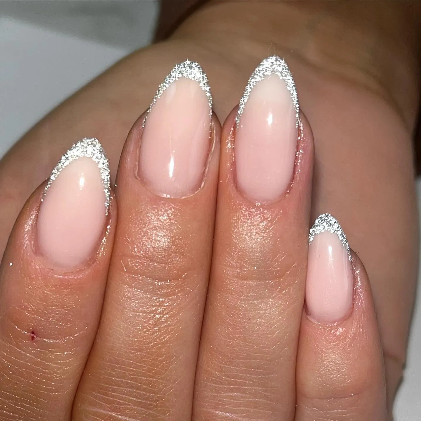 This almond-shaped French tip design keeps things simple and elegant with a fine silver glitter outline. A soft blush base gives that timeless, polished look, while the delicate glitter tracing the tips adds just enough sparkle to make it feel special. It’s a great example of how subtle glitter can elevate a traditional French manicure, making it suitable for everyday wear as well as occasions like weddings, parties, or New Year’s Eve.