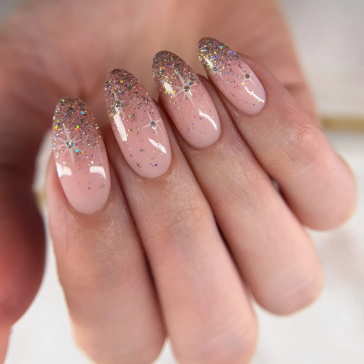 This blush pink French tip design adds a soft, magical twist with fine glitter and delicate star details. A sheer nude base keeps the look polished and wearable, while a subtle glitter fade at the tips creates that classic French shape with extra sparkle. Tiny star accents and crystal centres add interest without overwhelming the design, making this style easy to wear day to day while still feeling special. It’s a lovely option for occasions like weddings, New Year’s Eve, or any time you want something elegant with a hint of sparkle.