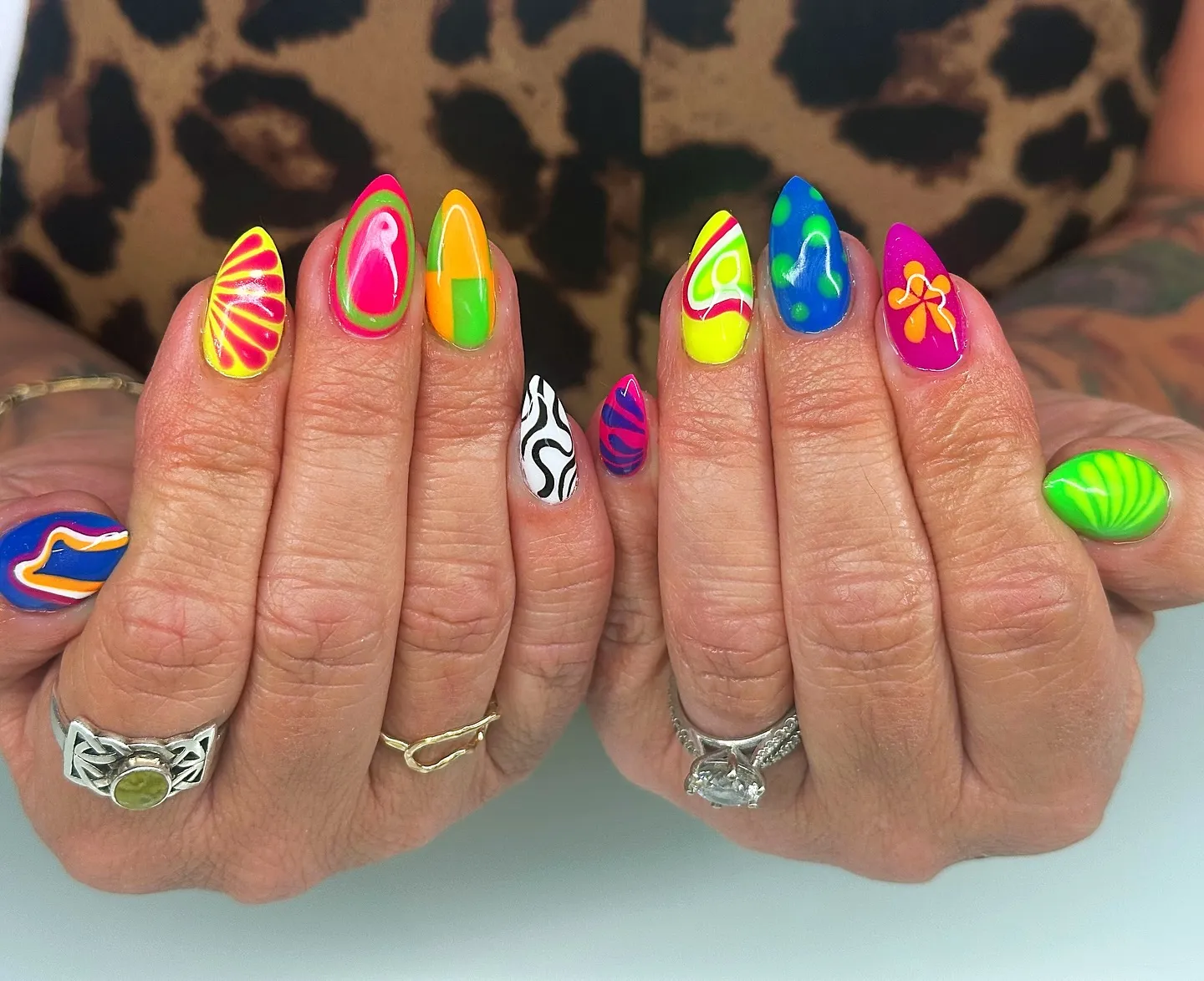 These long, almond-shaped nails are painted in ultra-bright neon shades of lime green, electric blue, hot pink, yellow, and orange. Each nail features a different bold design, including swirling abstract lines, wavy colour blocks, graphic stripes, and one black-and-white zebra-style accent, creating a playful mix-and-match look. The overall aesthetic is loud, expressive, and retro-inspired with a modern, high-gloss finish that feels fearless and fun. This vibrant nail set is perfect for summer festivals, holidays, or anytime you want your nails to be the statement.