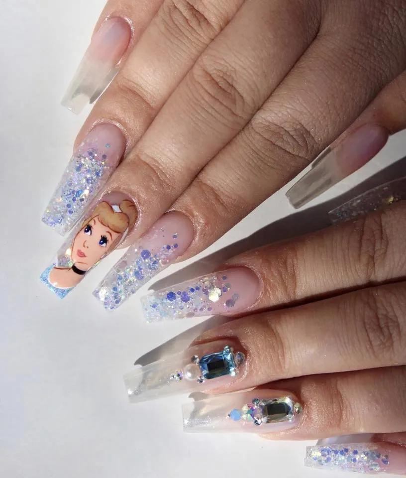 Sparkly and elegant, these Cinderella-inspired nails shimmer with soft glitter, icy blue tones, and rhinestone gems fit for a glass slipper moment. A dream come true for princess fans who love a touch of sparkle.