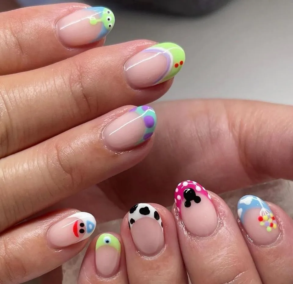 A subtle take on Pixar style! These Toy Story French tips use soft nude bases with bright pops of color inspired by Buzz, Woody, and the gang — a fun nod to the movies without going full costume mode.