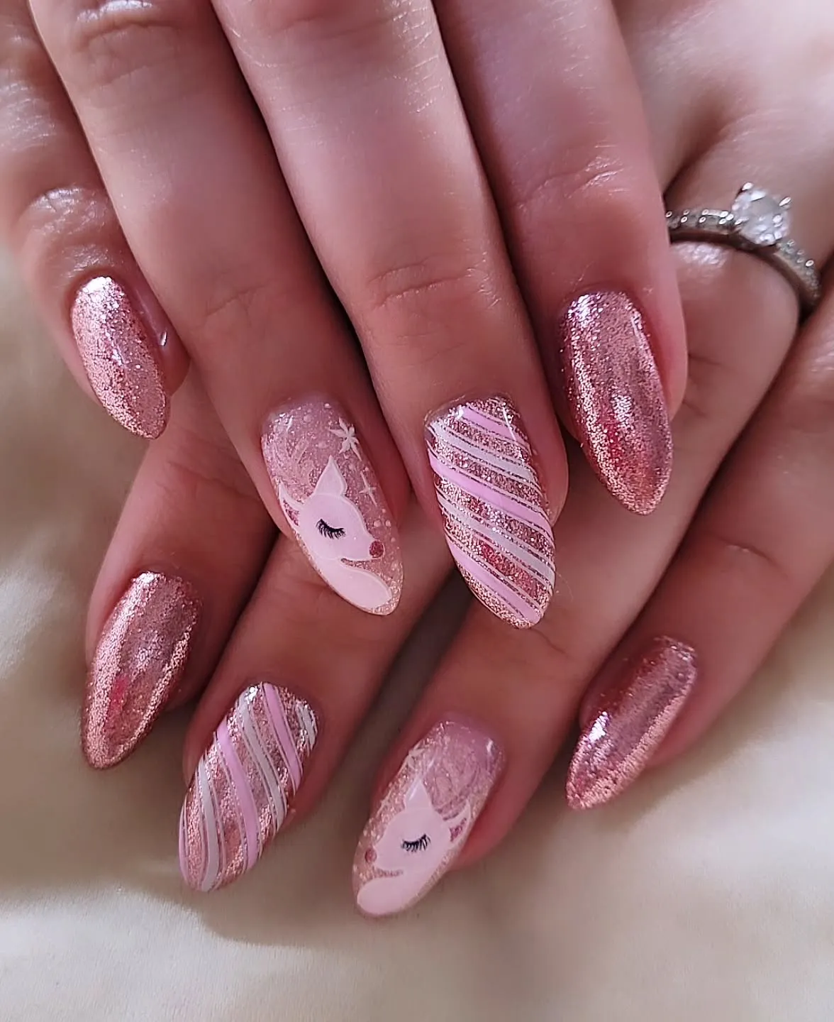 These rose-gold glitter nails with a sleepy reindeer accent are classy Christmas nails with a playful twist. If you want pink winter nails that sparkle under fairy lights, this one’s your go-to.