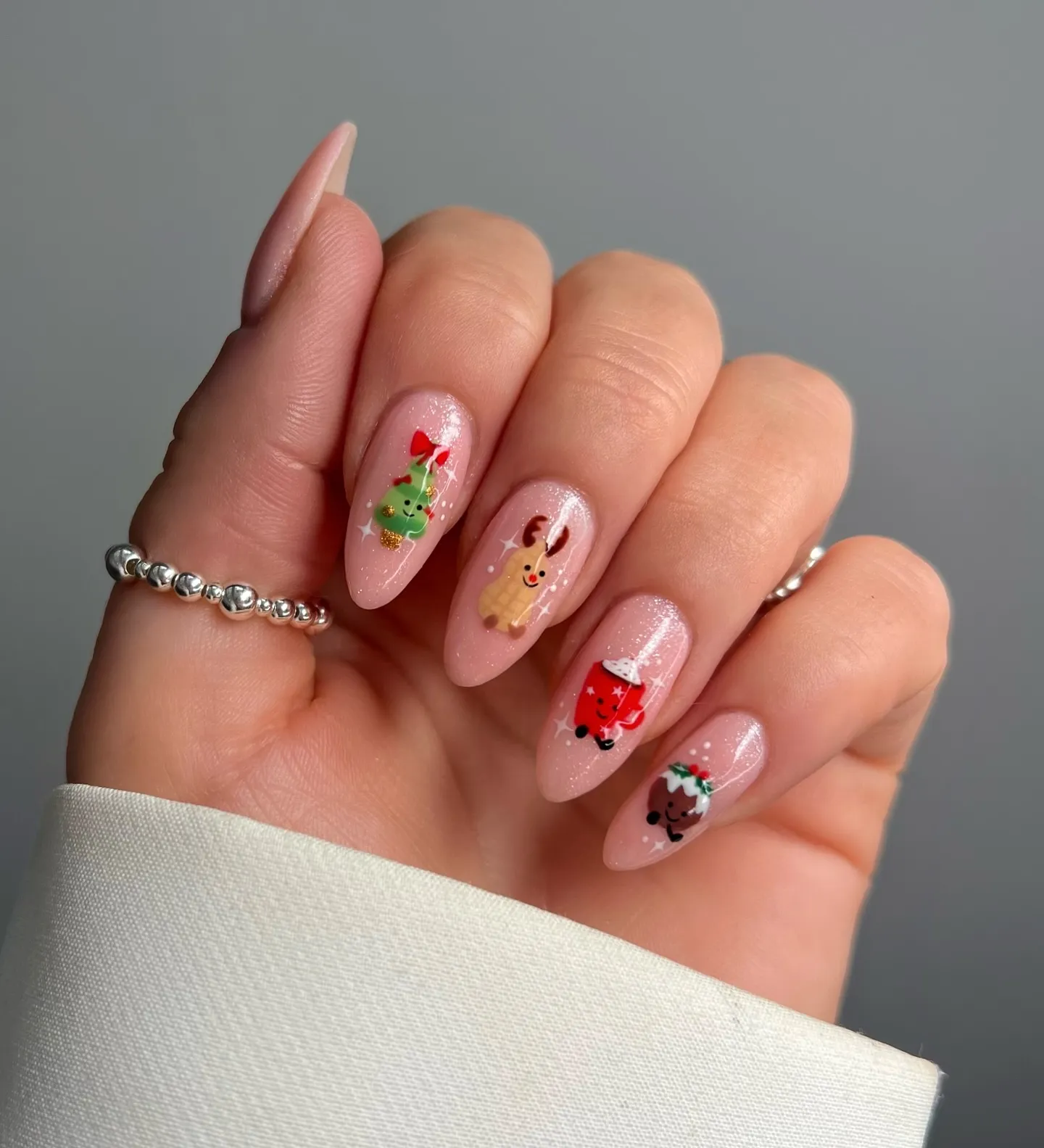 These cute Christmas nails by @nailsbyjanine.x_ feature tiny Jelly Cat inspired reindeer, Christmas trees, and puddings on a soft pink shimmer base. Simple, sweet, and perfect for short nails — total Christmas nails inspo for anyone who loves playful art.