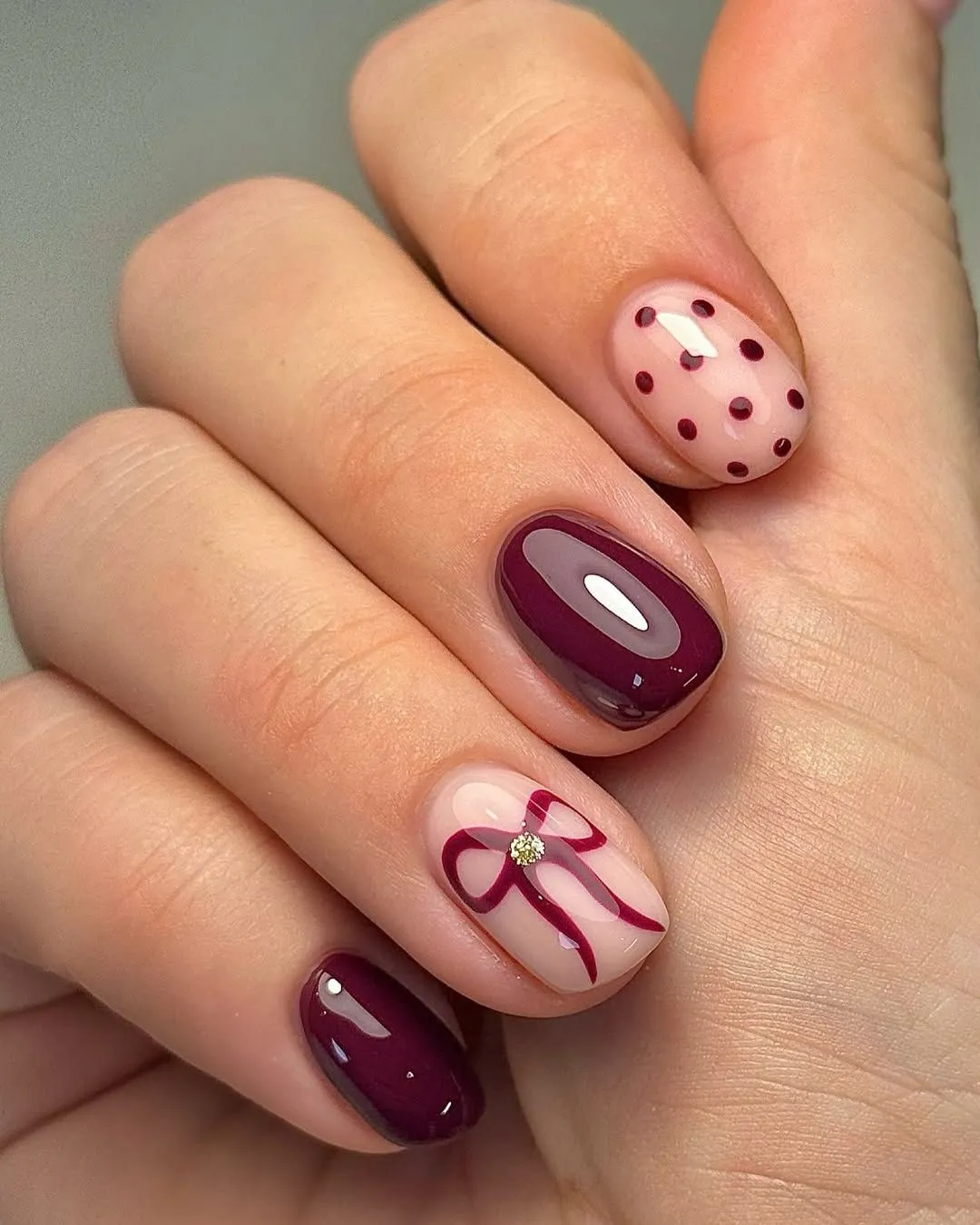 Deep burgundy polish and a dainty ribbon accent keep things classy for fall. This rich color combo is a great example of dark fall nails that still feel elegant and trendy.