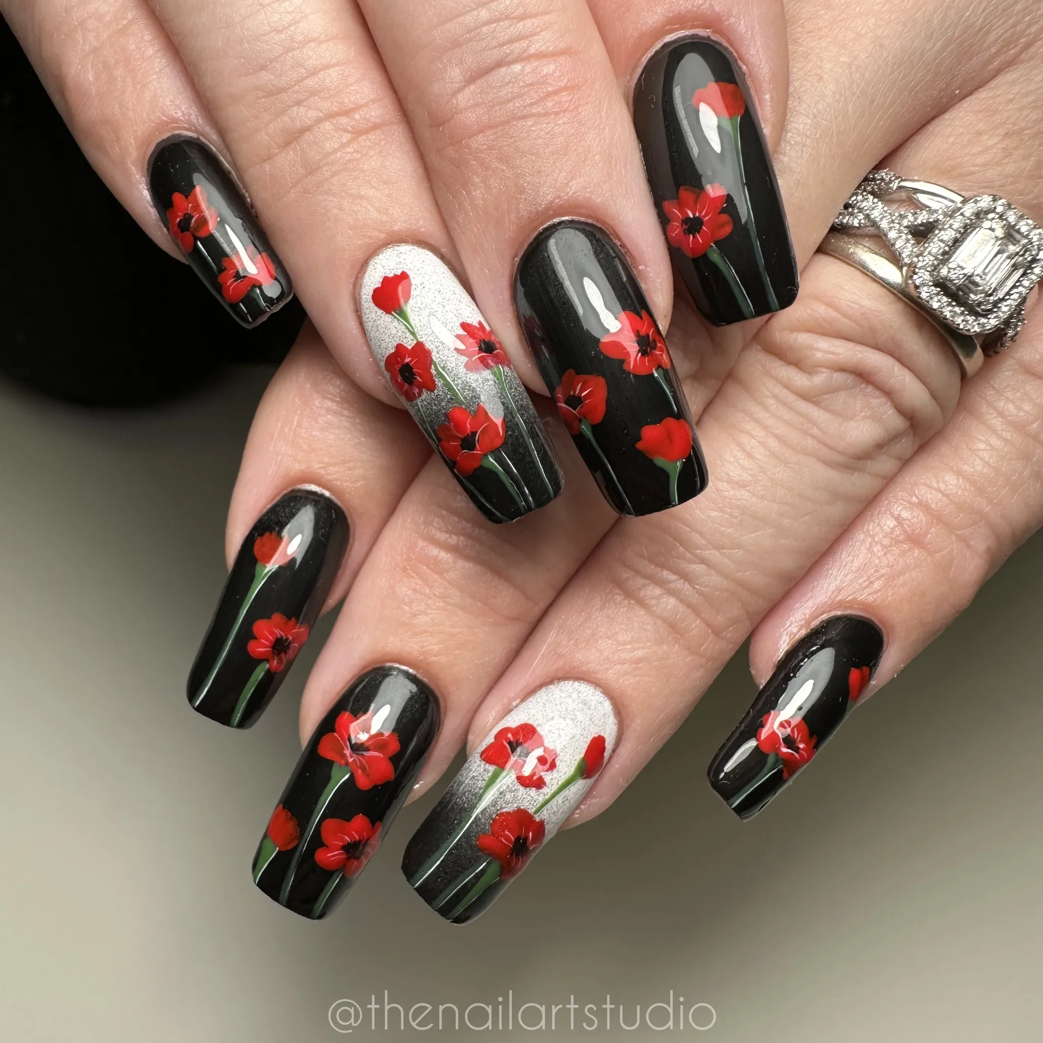 A timeless set that blends elegance with meaning — deep black nails adorned with hand-painted red poppies and a soft silver accent nail. The contrast makes every flower stand out beautifully, perfect for honoring Remembrance Day or Veterans Day in a subtle, graceful way. 💅 by @thenailartstudio